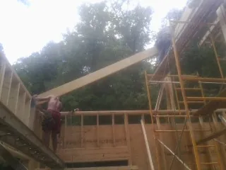 Carpenter raising a rafter beam on a new second story frame in Wanamingo