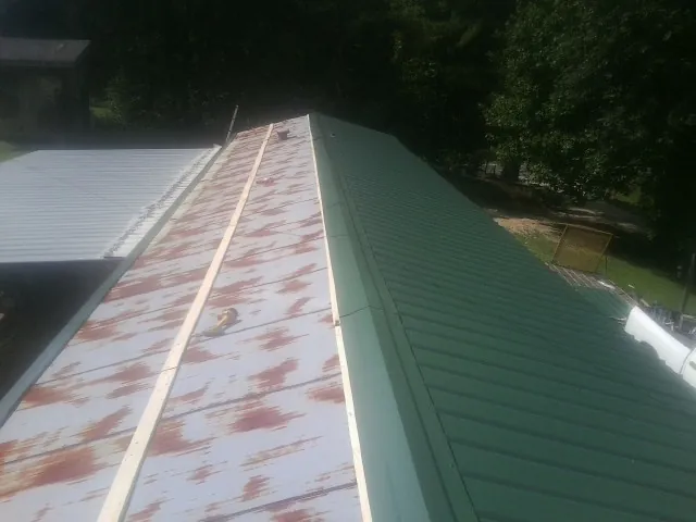 Old rusted panels beside newly installed green metal roofing — Wind Damage Roof Repair by Roofing Brothers in Wanamingo