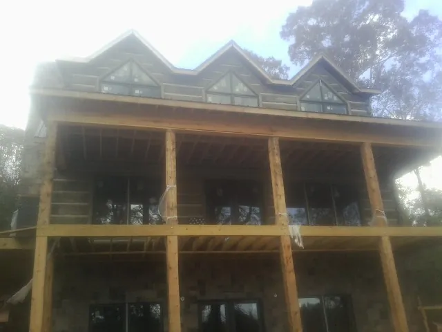Dormers and porch framing on a large log home under construction — Roof Coating work by our crew in Wanamingo