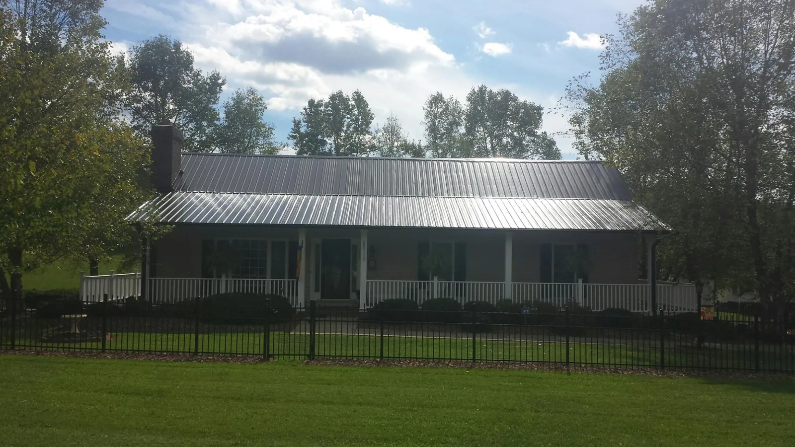 Gray metal roof on a brick ranch with a full width front porch — Gutter Guard Installation work by our crew in Wanamingo